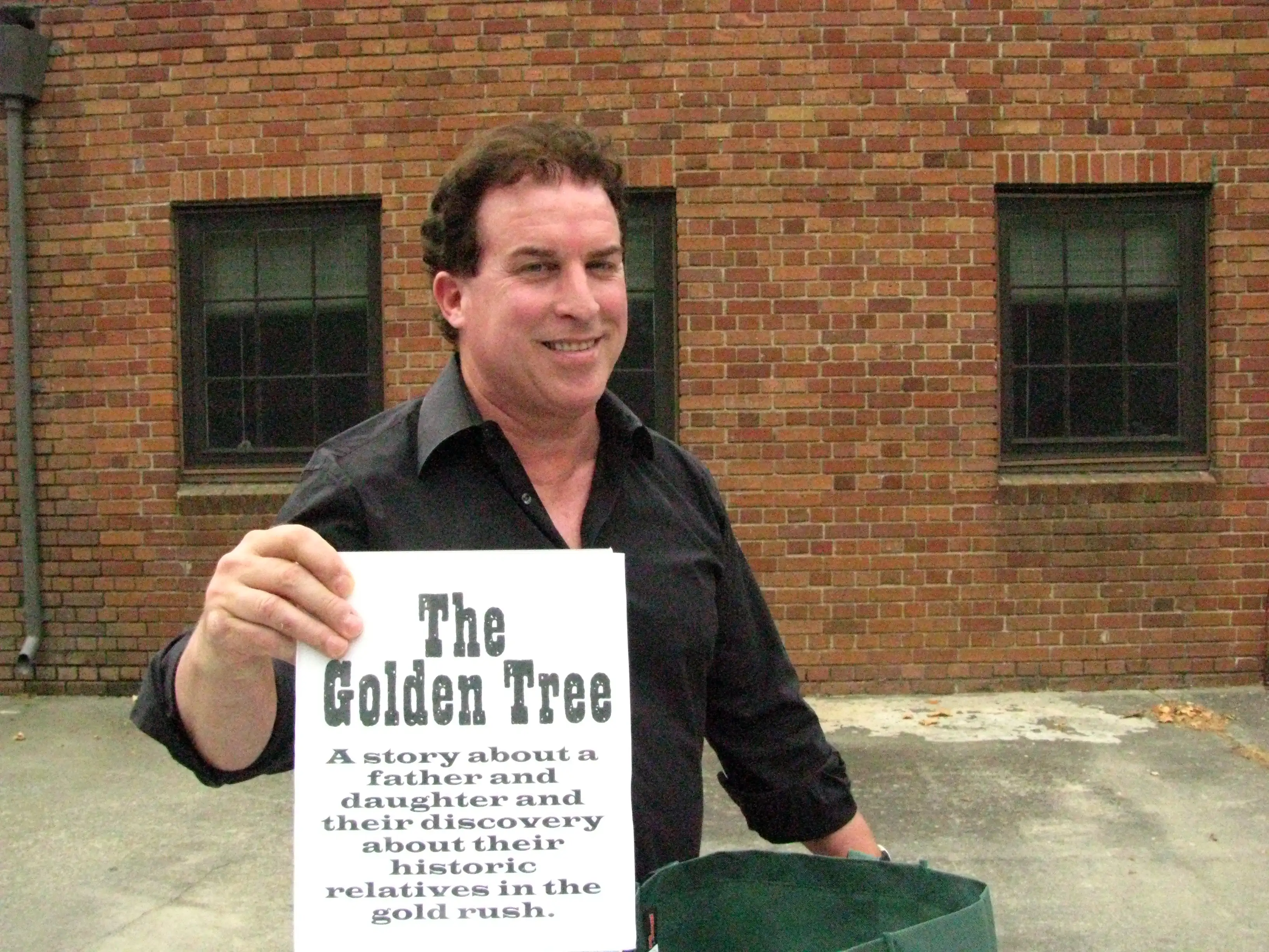 Gary Udell holding THE GOLdEN TREE (2010) sign for the table the 2010 cast and crew call.